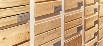 Ausstellung von verschiedenen gehobelten Holzprofilen mit Beschriftung, geeignet für Fassaden- und Innenverkleidung.