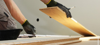 Handwerker verlegt Holzfußboden – Symbol für professionelle Montage- und Verlegeservices.