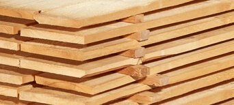 Gestapelte Schalbretter aus Holz mit sägerauer Oberfläche, ideal für den Bau- und Konstruktionsbereich.
